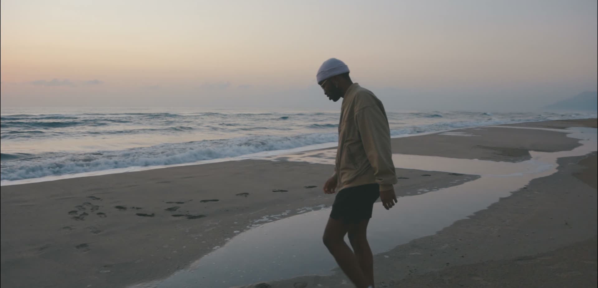 A traveller walking along the shoreline at dusk